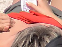 Amateur female is spied lying on the beach and erotically creaming the nude downblouse tits with the sun lotion.