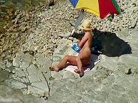 The absolutely naked female getting suntanned on the beach was voyeured on the camera by our kinky hunter!