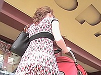Amateur female in a light summer dress is walking with the buggy and does not care about the wind that demonstrates her upskirt to the street public.